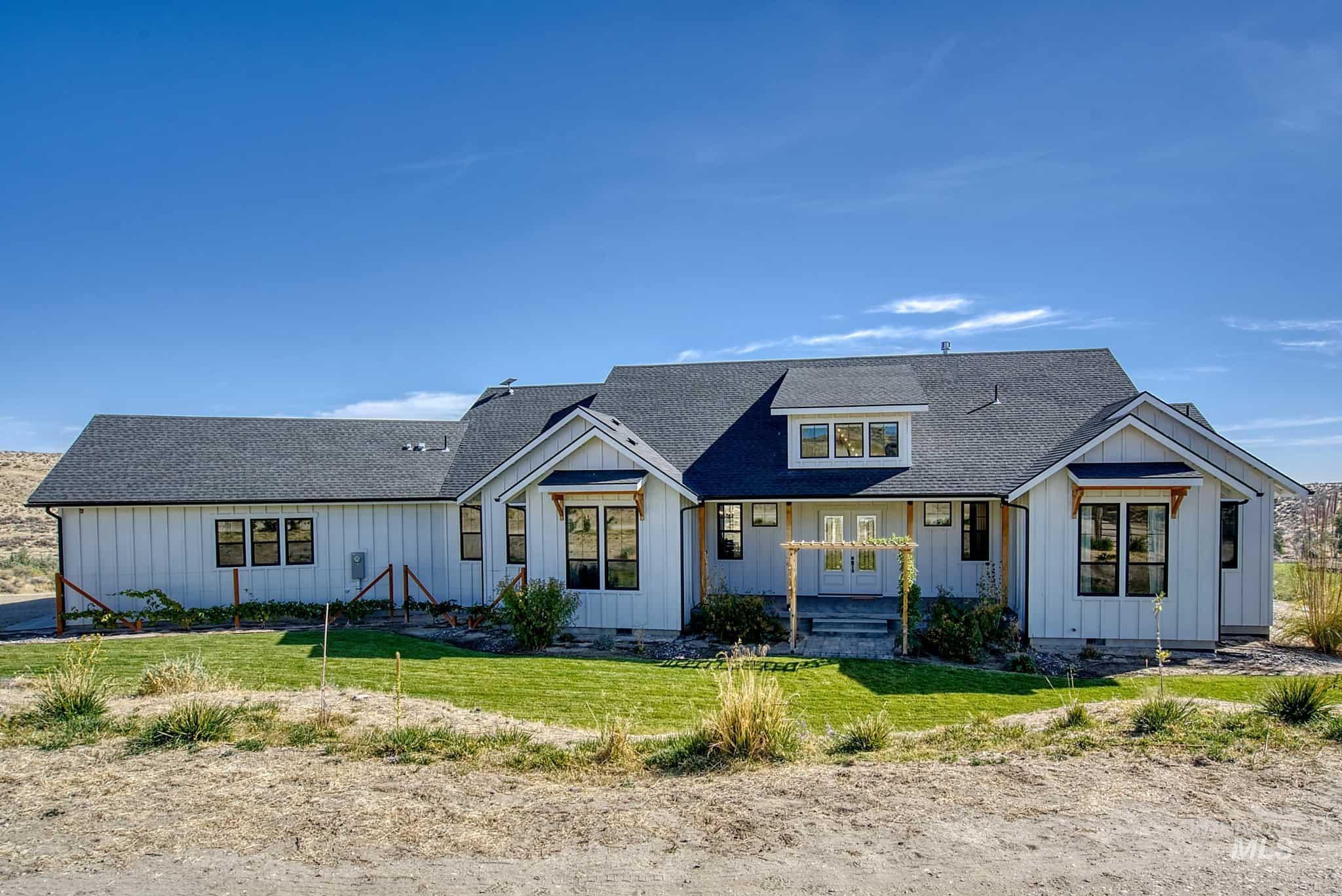 876 Coyote Gulch Road Adrian, OR 97901 - Photo 47 of 50 White board and batten exterior with black-framed windows, a dark shingle roof, and a front entry pergola