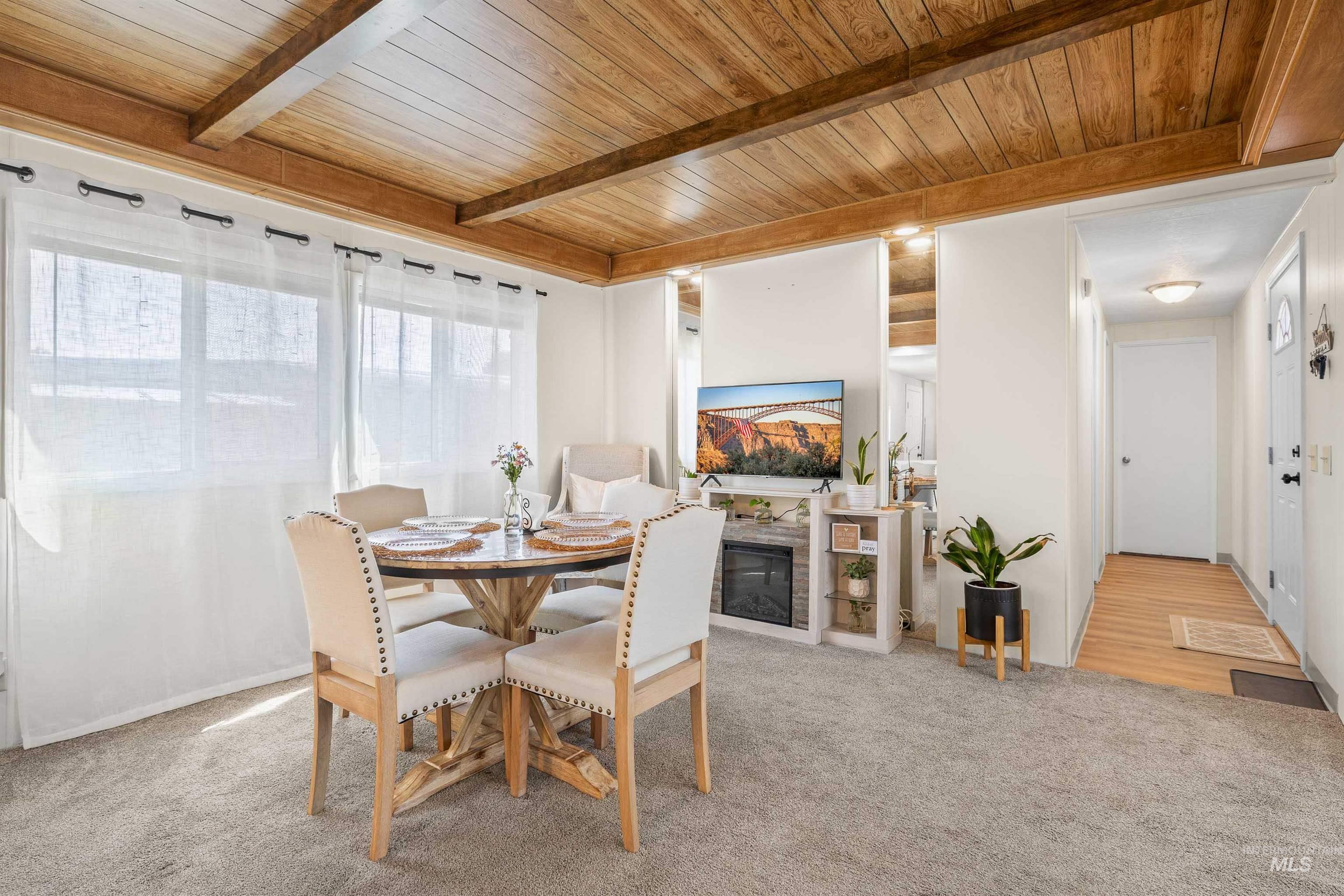 198 South Hills Road, Unit 115 Twin Falls, ID 83301 - Photo 3 of 22 Dining space with a wooden ceiling with exposed beams, light colored carpet, and a glass covered fireplace