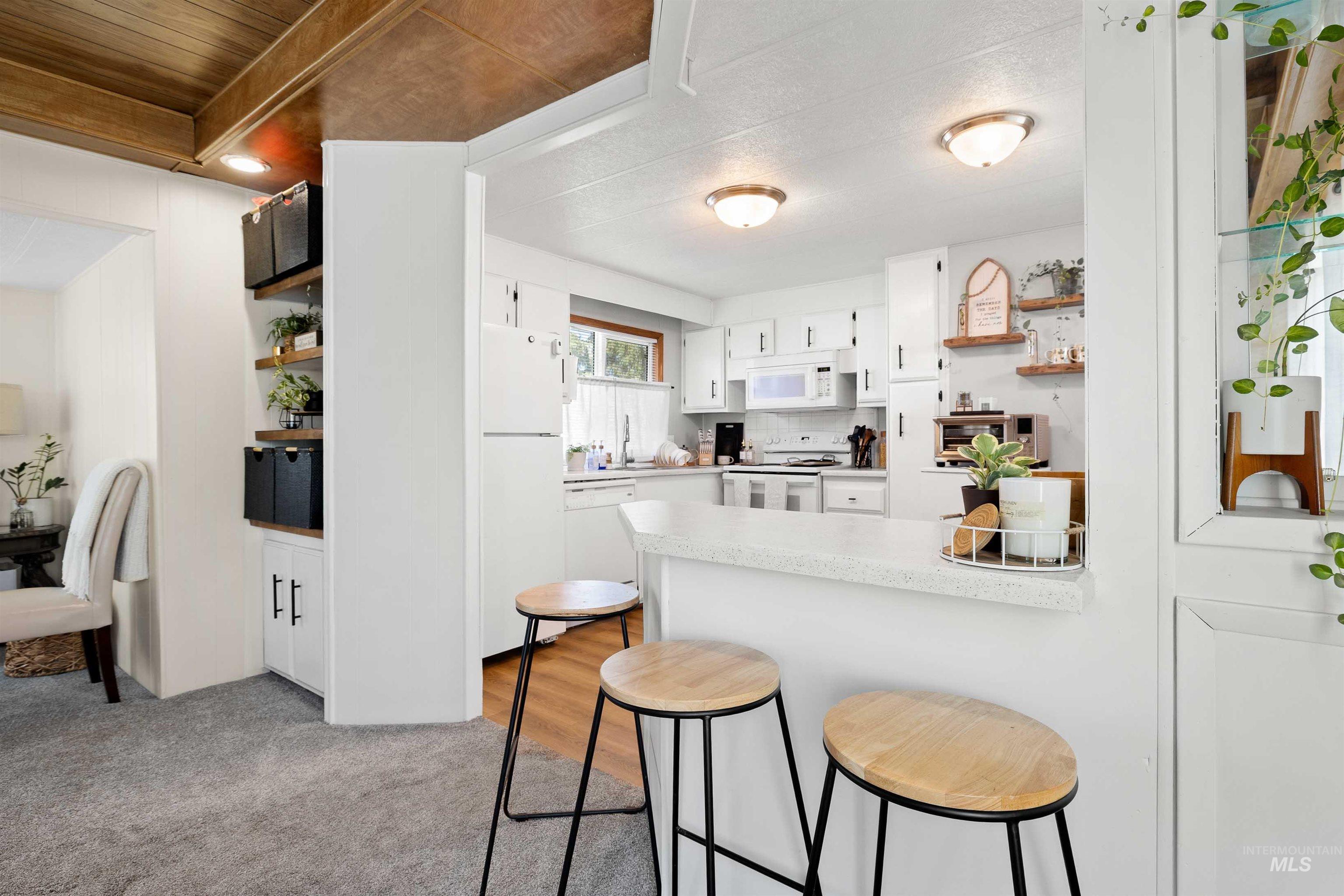 198 South Hills Road, Unit 115 Twin Falls, ID 83301 - Photo 4 of 22 Kitchen featuring white cabinetry, a kitchen breakfast bar, white appliances, light countertops, and open shelves