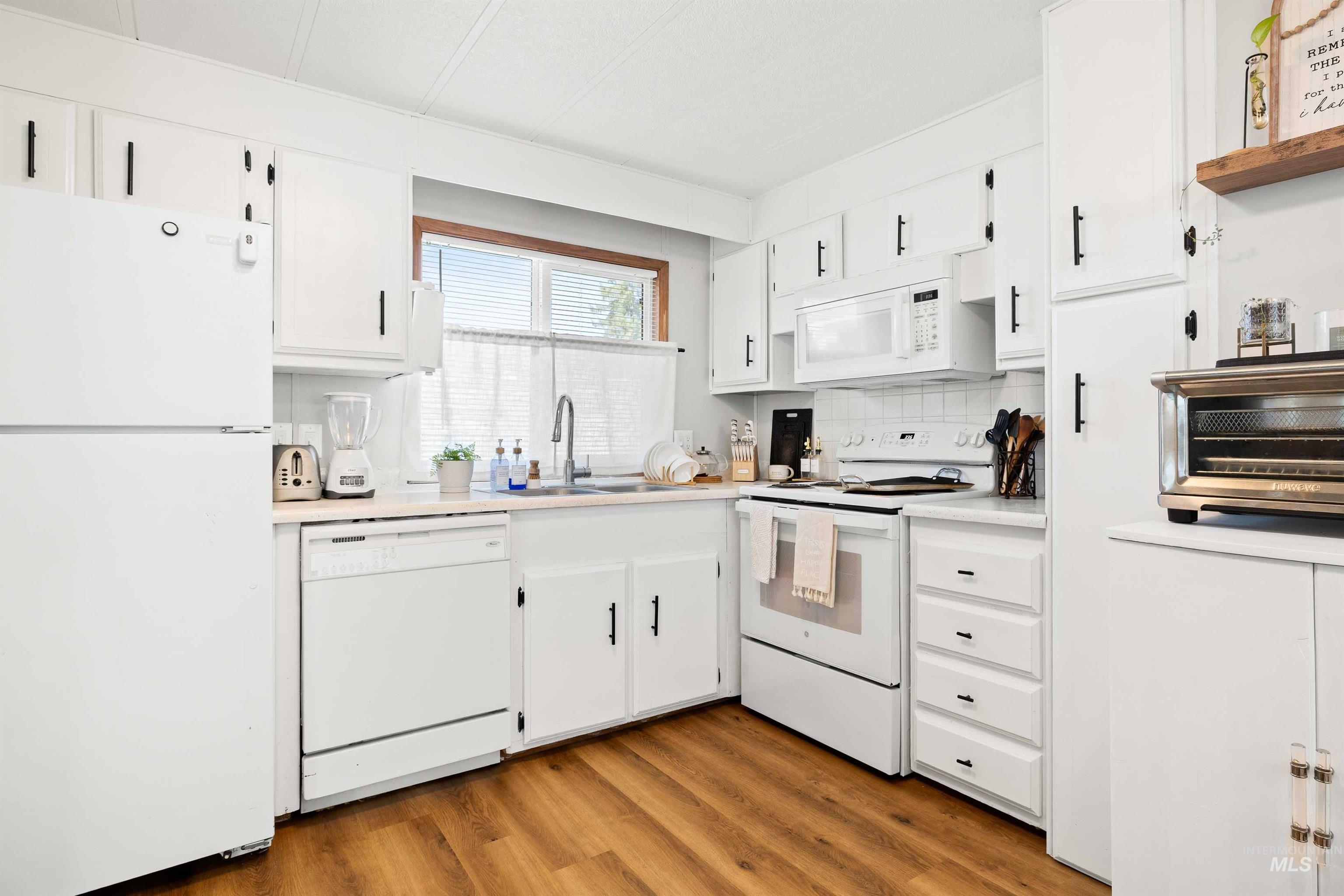 198 South Hills Road, Unit 115 Twin Falls, ID 83301 - Photo 5 of 22 Kitchen featuring white appliances, light countertops, white cabinets, and light wood-style floors