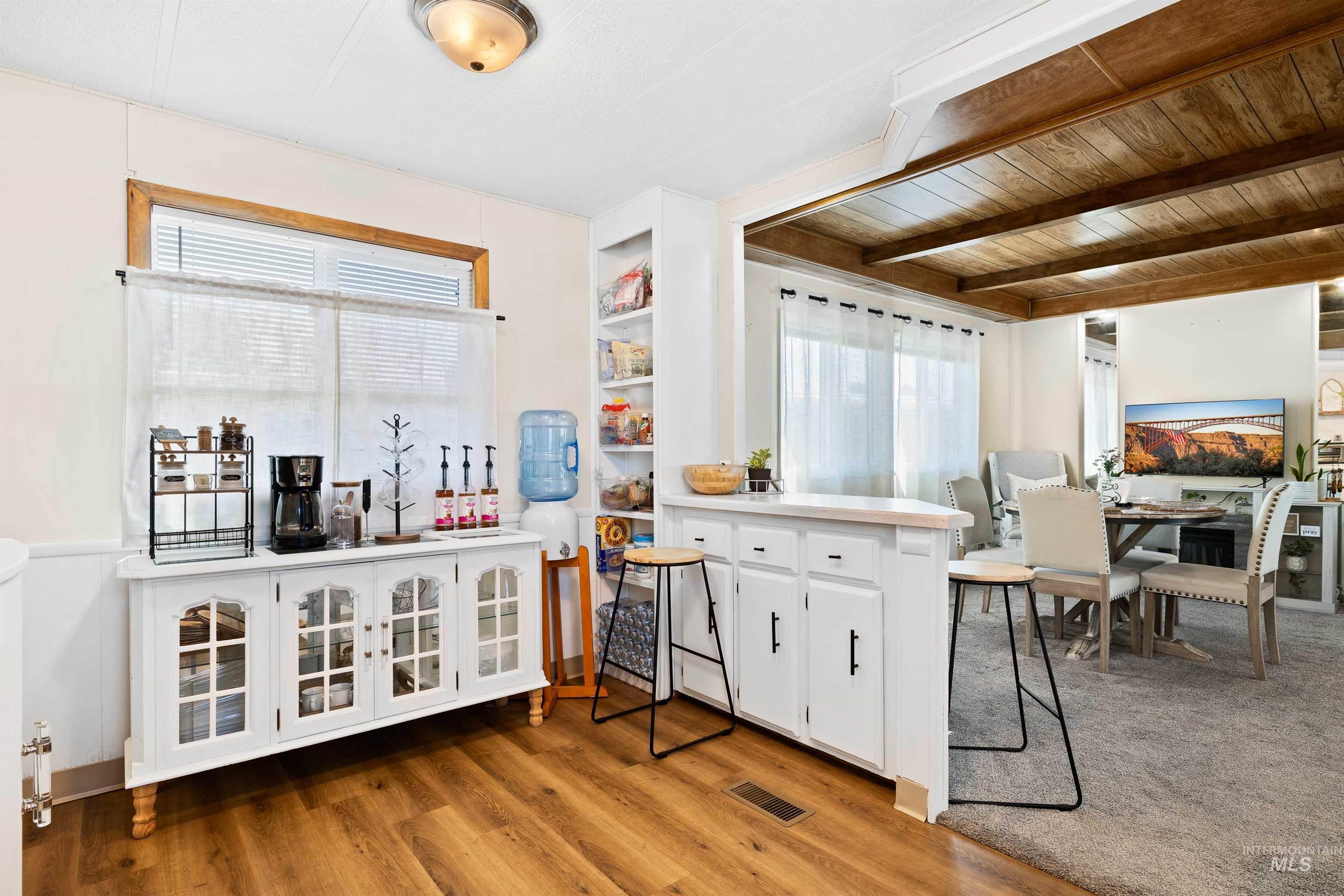 198 South Hills Road, Unit 115 Twin Falls, ID 83301 - Photo 7 of 22 Kitchen with white cabinets, healthy amount of natural light, light countertops, light wood-style floors, and a wooden ceiling with exposed beams