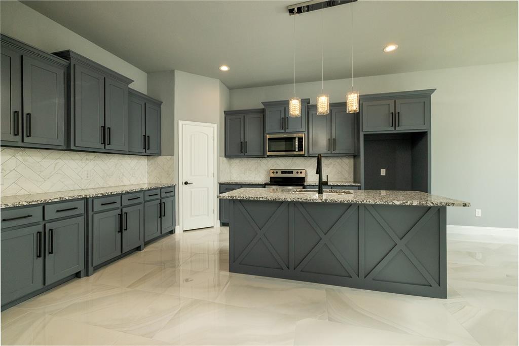 a kitchen with stainless steel appliances granite countertop a sink a stove a microwave a counter top and cabinets