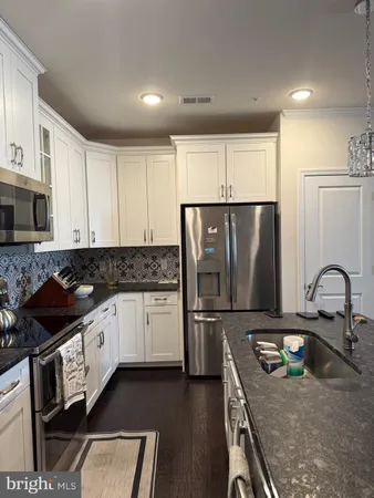 a kitchen with granite countertop a refrigerator stove and sink