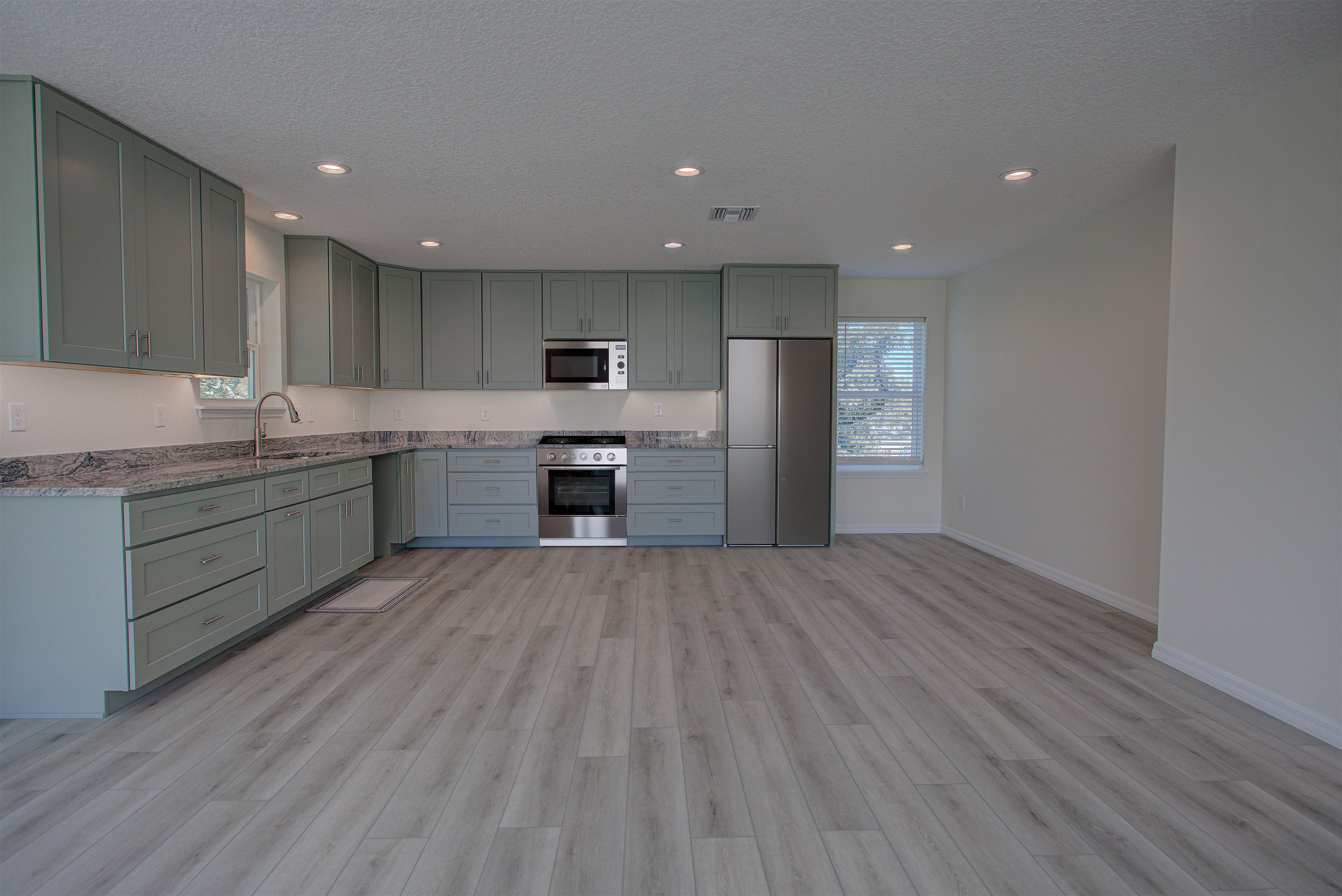 253 Desoto Road St. Augustine, FL 32080 - Photo 22 of 25 Kitchen with stainless steel appliances, recessed lighting, light wood-style floors, light stone countertops, and a textured ceiling