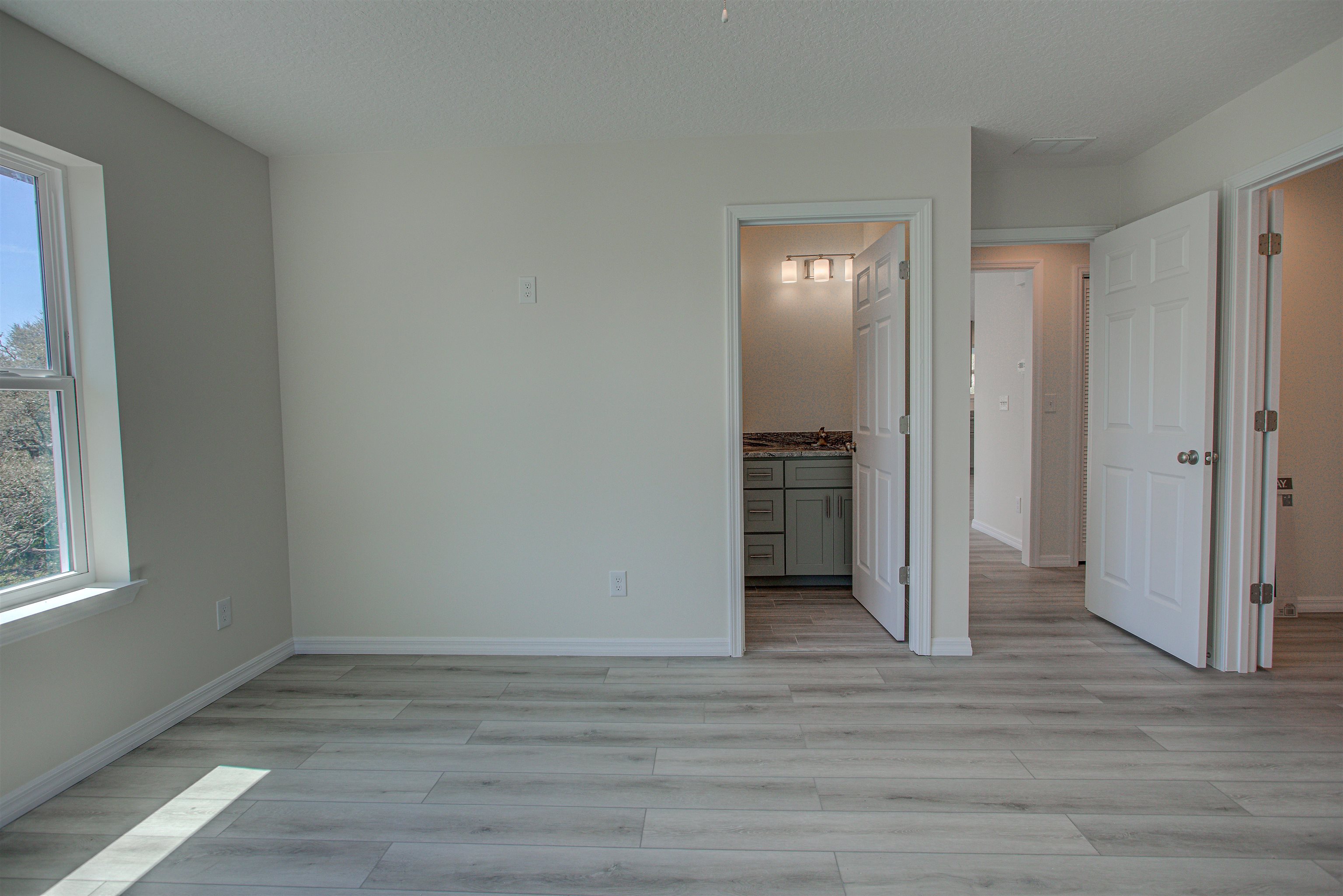 253 Desoto Road St. Augustine, FL 32080 - Photo 9 of 25 Unfurnished bedroom featuring light wood finished floors, ensuite bath, and a textured ceiling