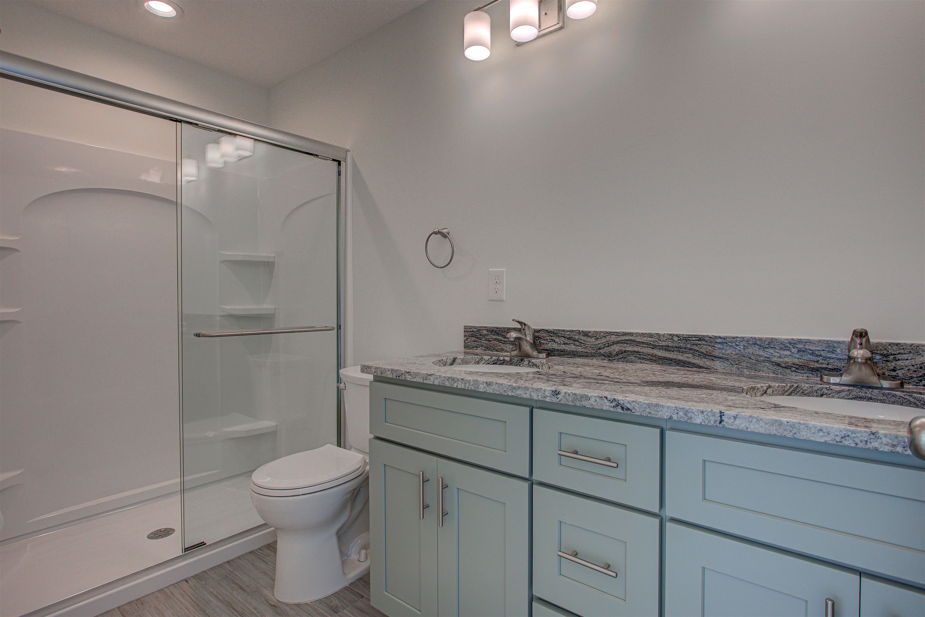 253 Desoto Road St. Augustine, FL 32080 - Photo 10 of 25 Bathroom with double vanity, a shower stall, and light wood-style flooring