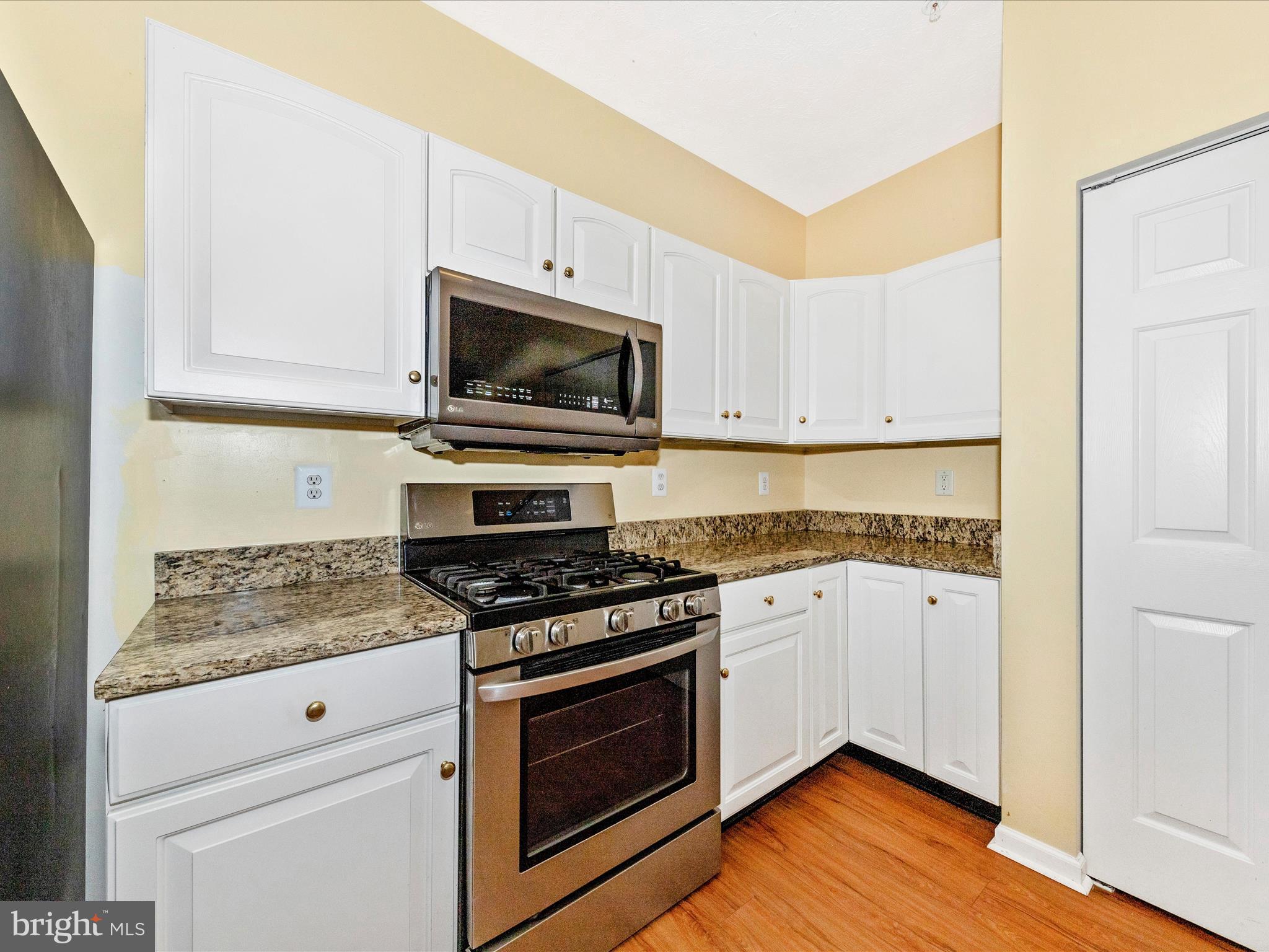 6125 Springwater Place, Unit K Frederick, MD 21701 - Photo 11 of 63 a kitchen with granite countertop cabinets stainless steel appliances and wooden floor