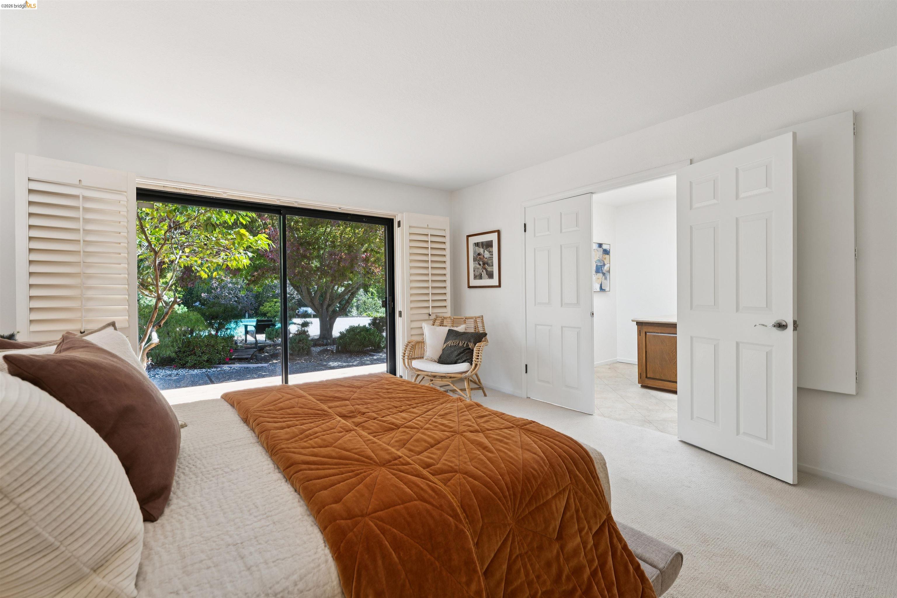 7 Jo Lin Court El Sobrante, CA 94803 - Photo 68 of 99 Bedroom featuring expansive glass sliding doors, white plantation shutters, neutral carpeting, and a pair of six-panel interior doors