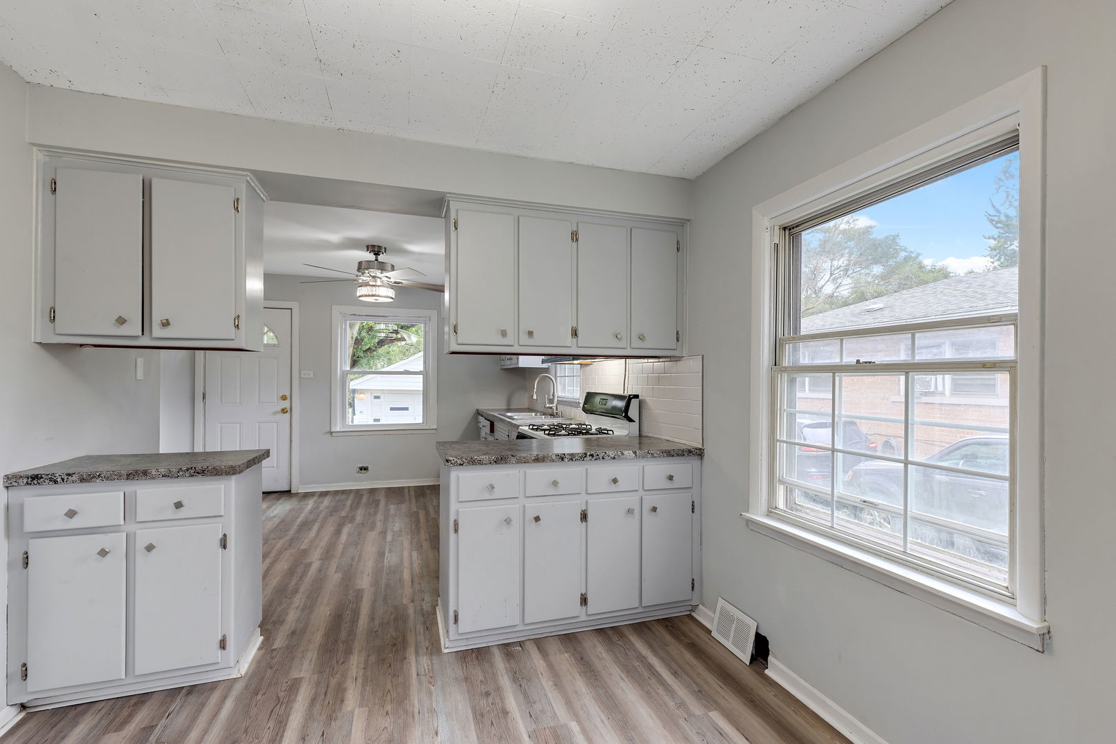 320 Streamside Drive Harvey, IL 60426 - Photo 5 of 26 a kitchen with granite countertop a stove a sink dishwasher and white cabinets with wooden floor