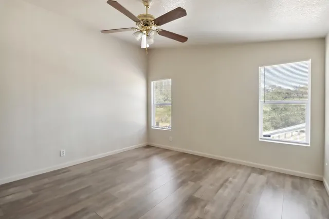 an empty room with wooden floor and windows