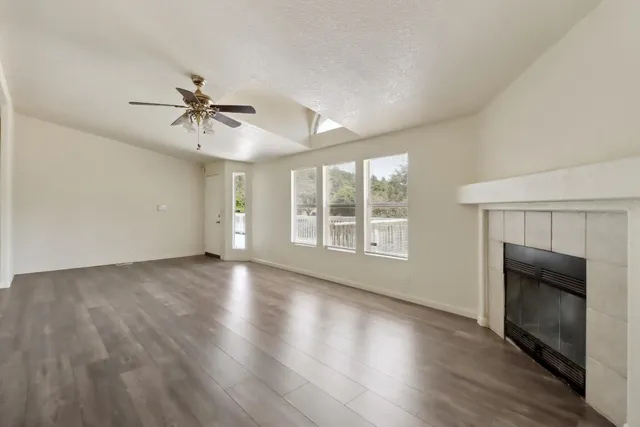 a view of an empty room with a fireplace and wooden floor