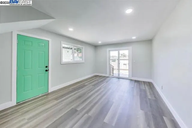 an empty room with wooden floor and windows