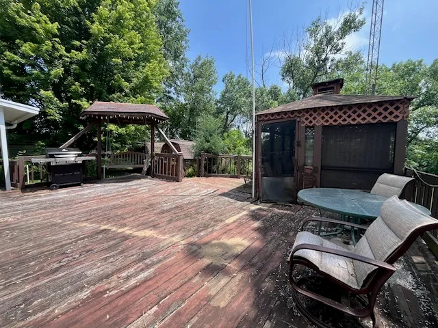 a view of a roof deck with table and chairs under an umbrella with wooden floor and fence