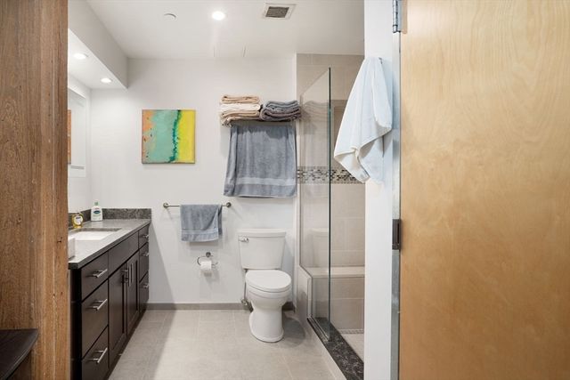 a bathroom with a granite countertop toilet sink and mirror