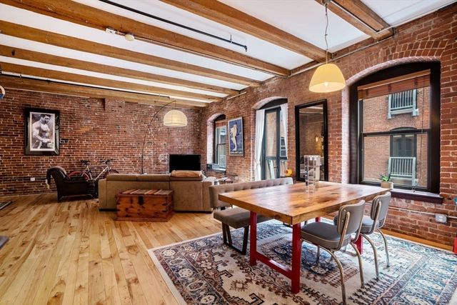 a view of a dining room and livingroom with furniture wooden floor a rug and a chandelier