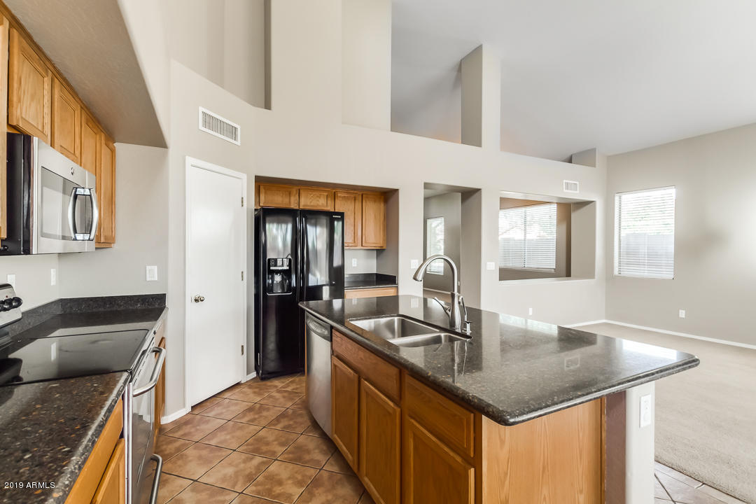 15917 West Calavar Road Surprise, AZ 85379 - Photo 11 of 40 a kitchen with stainless steel appliances granite countertop a sink refrigerator and cabinets