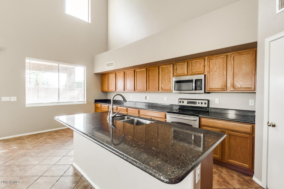 15917 West Calavar Road Surprise, AZ 85379 - Photo 36 of 40 a kitchen with stainless steel appliances granite countertop a sink a stove and cabinets