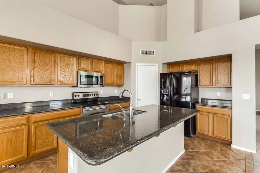 15917 West Calavar Road Surprise, AZ 85379 - Photo 8 of 40 a kitchen with stainless steel appliances granite countertop a sink a stove and refrigerator