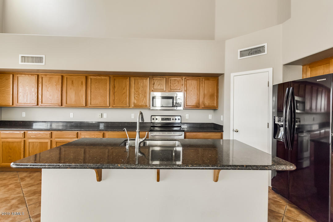 15917 West Calavar Road Surprise, AZ 85379 - Photo 9 of 40 a kitchen with granite countertop a sink and stainless steel appliances