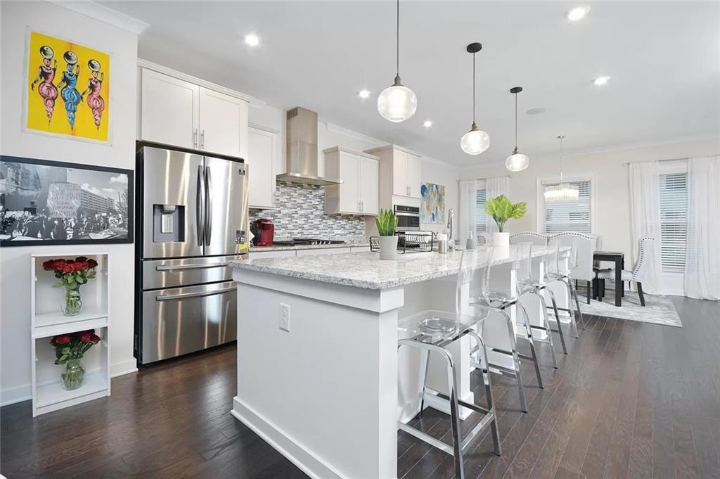 2048 Holtz Lane Atlanta, GA 30318 - Photo 6 of 27 a kitchen with stainless steel appliances kitchen island granite countertop a refrigerator a stove a sink a dining table and chairs with wooden floor