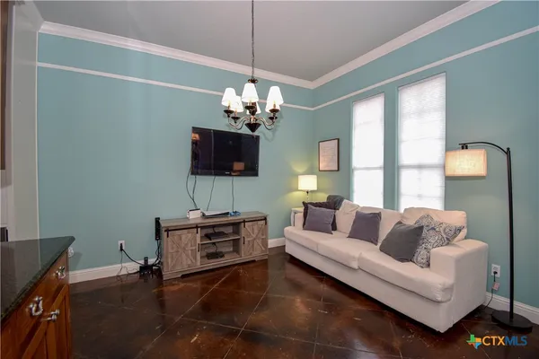 a living room with furniture a chandelier and a flat screen tv
