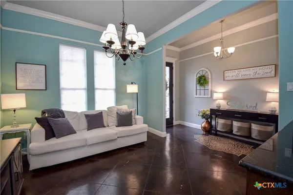 a living room with furniture a chandelier and a flat screen tv