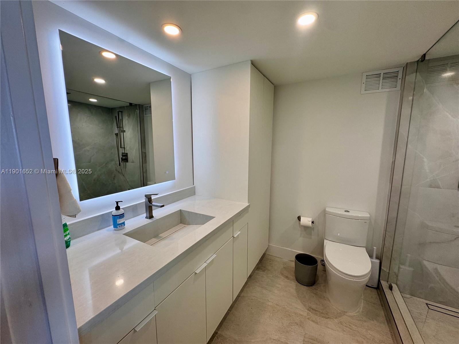 2899 Collins Avenue, Unit 1414 Miami Beach, FL 33140 - Photo 5 of 26 a bathroom with a double vanity sink toilet and mirror