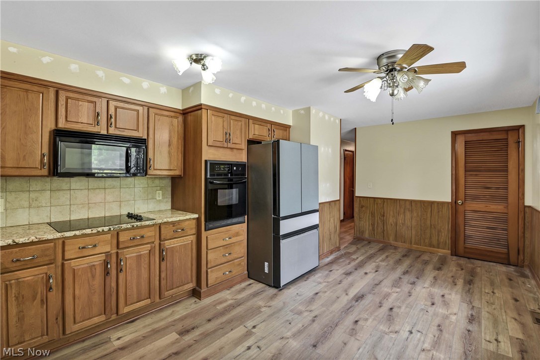 301 Crosse Road Amherst, OH 44001 - Photo 22 of 49 Kitchen featuring wood-finish cabinetry, granite-style countertops, an integrated cooktop, a built-in oven, and wood-finish flooring