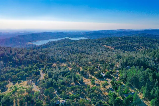 an aerial view of residential house with green space and mountain view in back