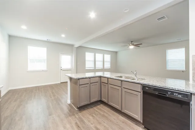 a large kitchen with granite countertop a sink and dishwasher stove top oven with wooden floor