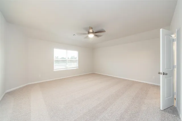an empty room with a window and a ceiling fan