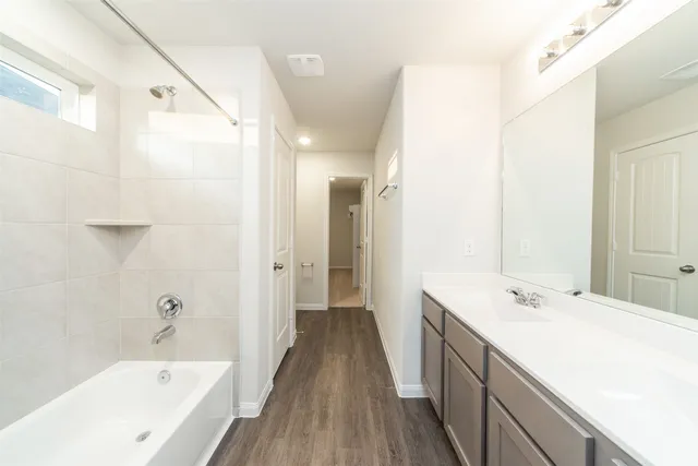 a bathroom with a tub sink shower and two mirror