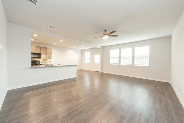 a view of an empty room with a window and wooden floor