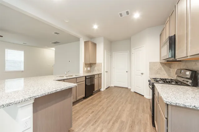 a kitchen with granite countertop a sink stove and cabinets