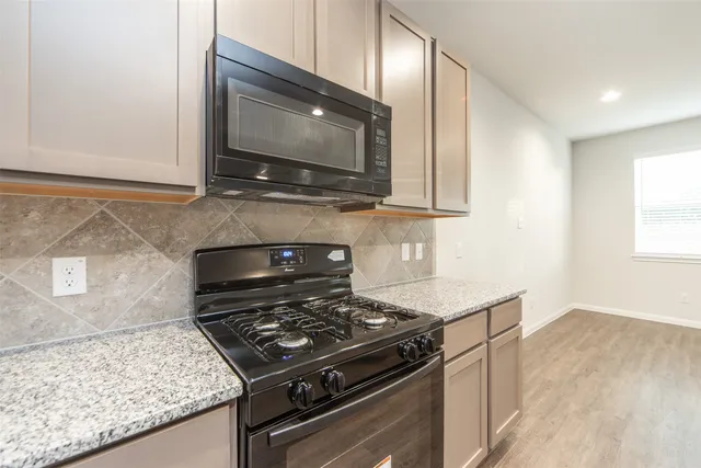 a kitchen with granite countertop a stove and a microwave