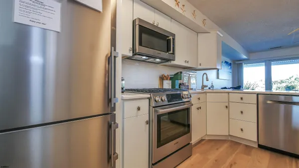 a kitchen with stainless steel appliances white cabinets white stove a microwave and a refrigerator