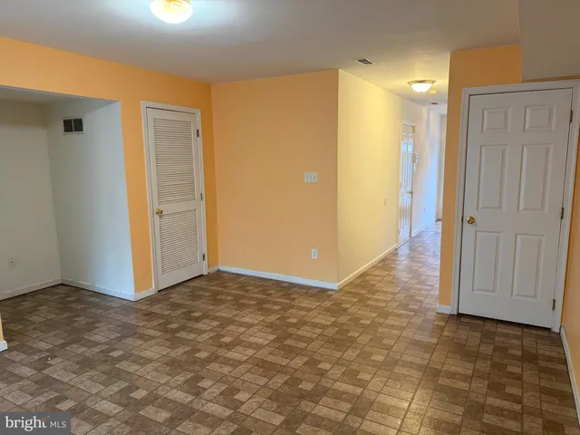 an empty room with wooden floor fireplace and windows