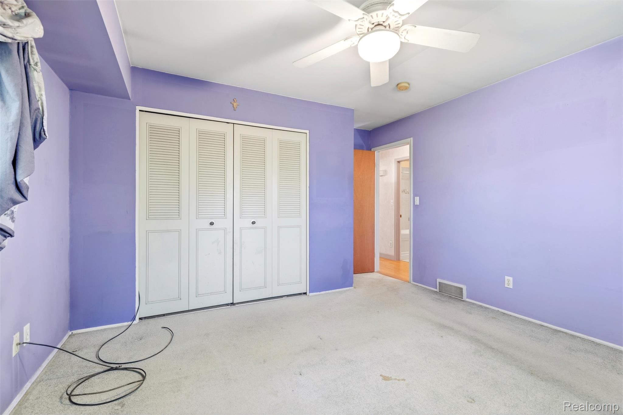 309 Windy Bluff Street Flushing, MI 48433 - Photo 15 of 32 Bedroom featuring white louvered bifold closet doors, light-colored carpet flooring, and a ceiling fan with integrated lighting