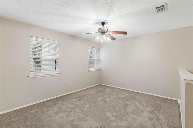 an empty room with closet and a ceiling fan