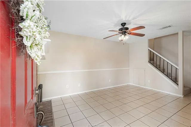 a view of an empty room and chandelier fan