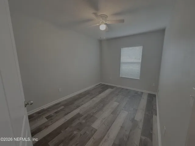 a view of a room with wooden floor and a ceiling fan