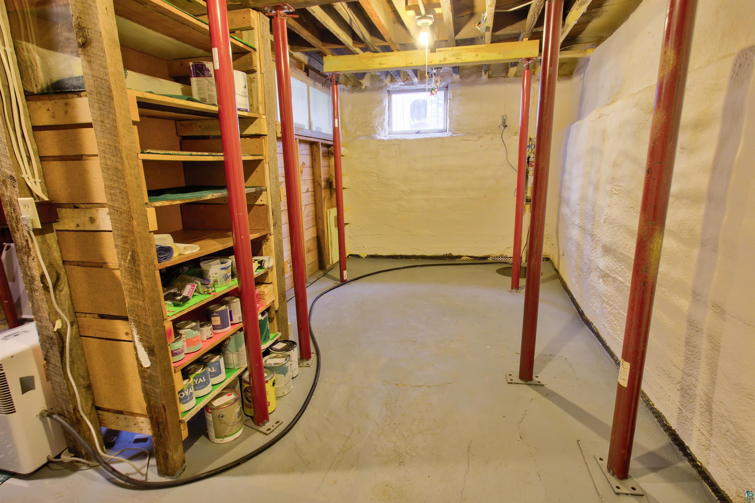 24 East Conan Street Ely, MN 55731 - Photo 24 of 27 Unfinished basement offering ample storage with built-in wooden shelving, exposed ceiling joists, and a concrete floor