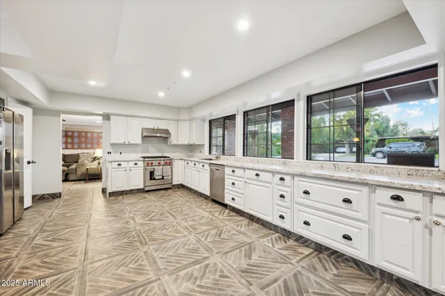 a large white kitchen with a large window and stainless steel appliances