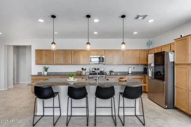 a kitchen with stainless steel appliances granite countertop a sink a stove a refrigerator and island with wooden floor