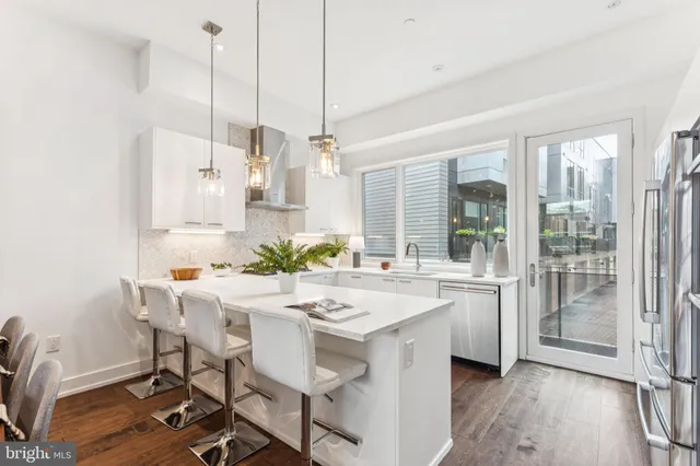 a kitchen with stainless steel appliances kitchen island granite countertop a table chairs and white cabinets