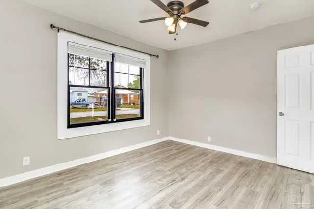 a view of an empty room with wooden floor and a window