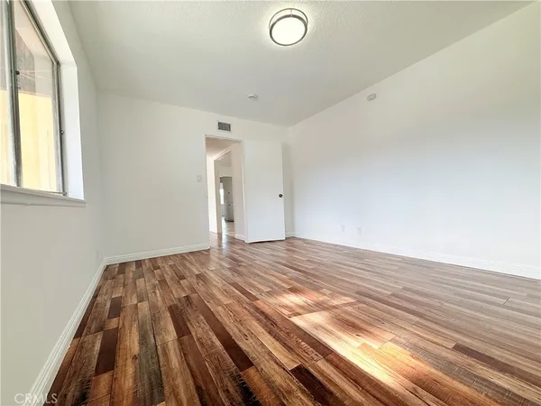 a view of empty room with window and wooden floor