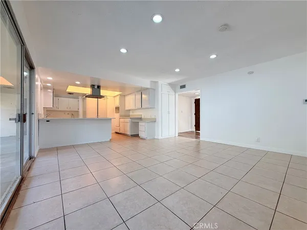 a view of an empty room and a kitchen