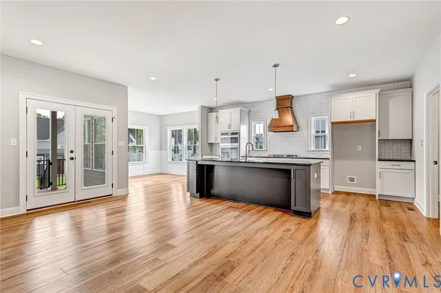 a large kitchen with stainless steel appliances kitchen island wooden floors and granite counter tops