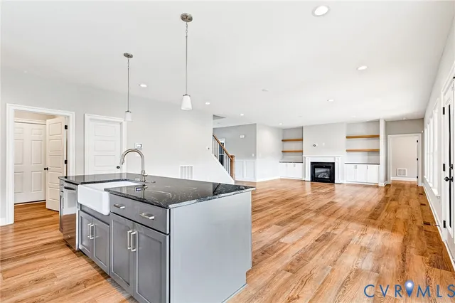 a kitchen with stainless steel appliances granite countertop a sink a stove and a wooden floors